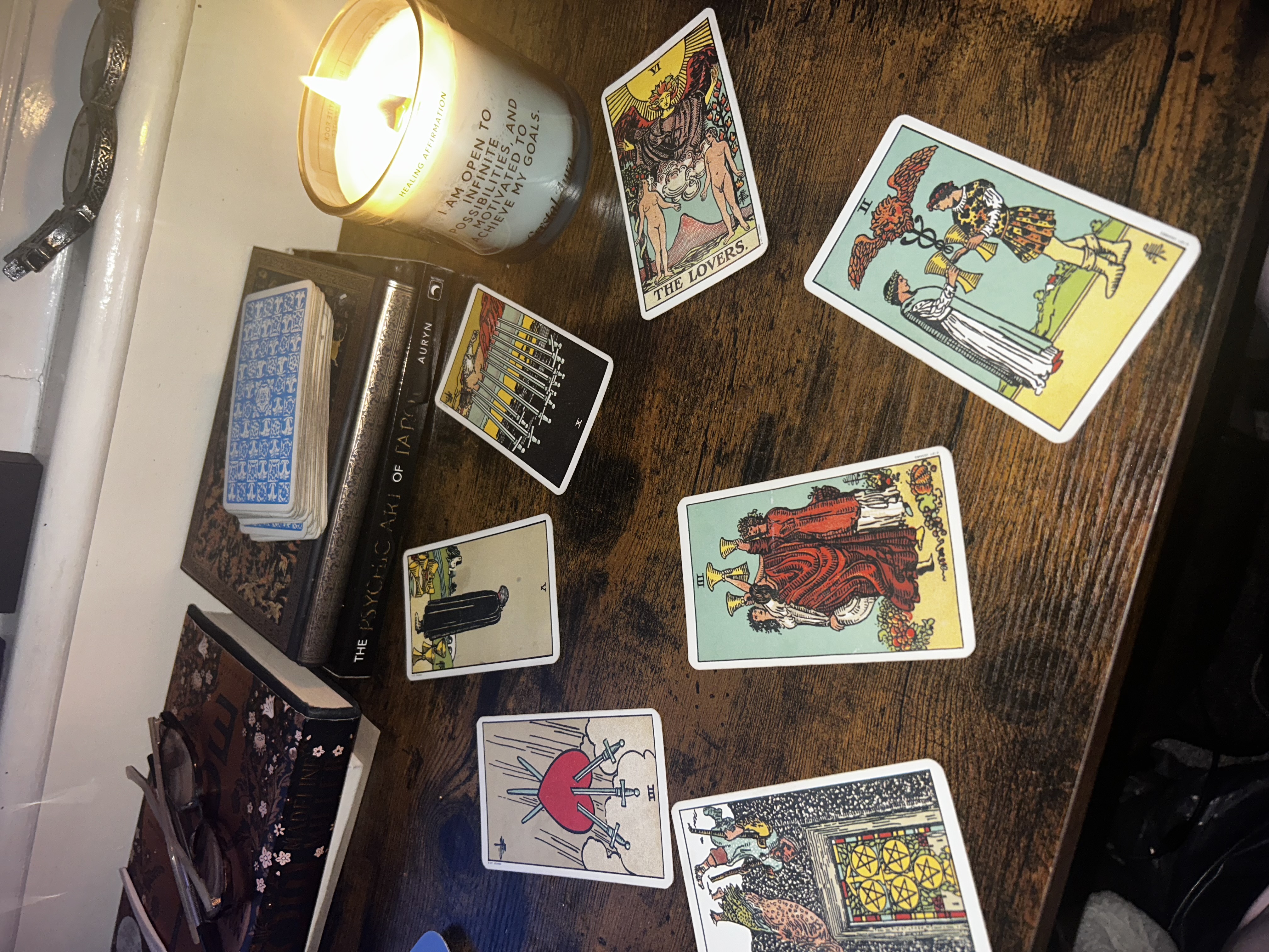 Tarot card spread laid out on a wooden table with a lit candle