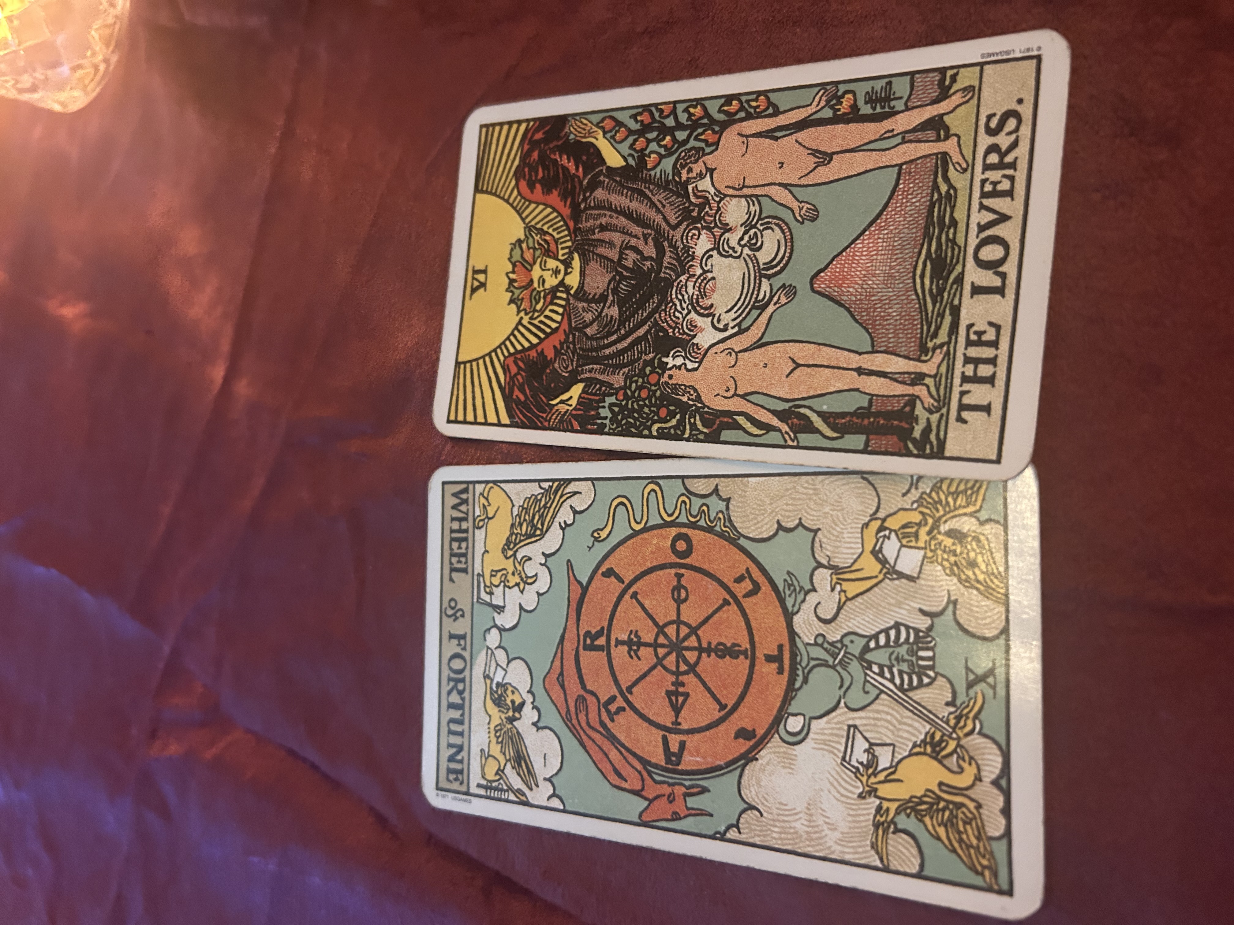 Two tarot cards displayed on a purple fabric surface