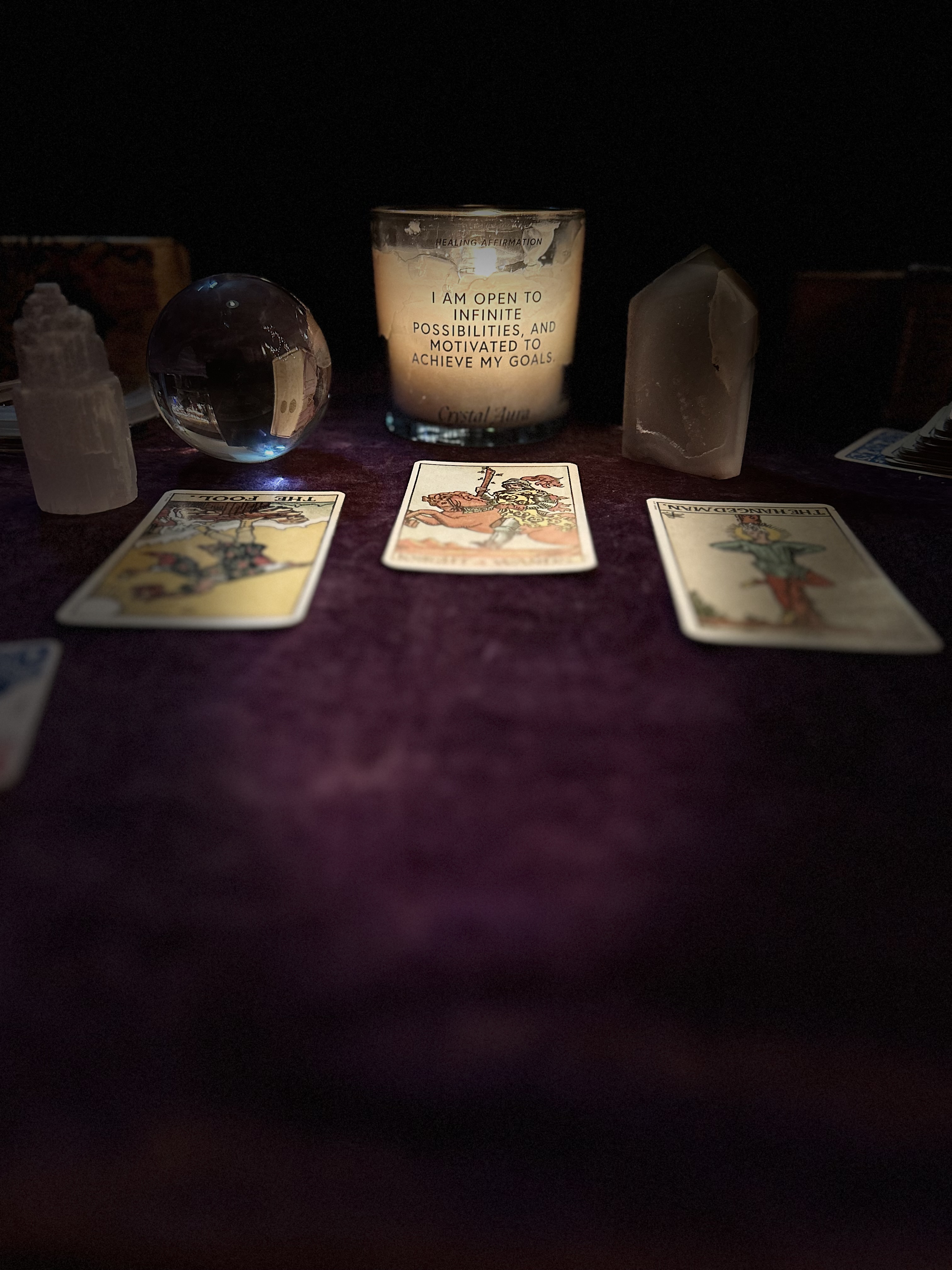Tarot reading setup with cards, a crystal ball and an affirmation candle