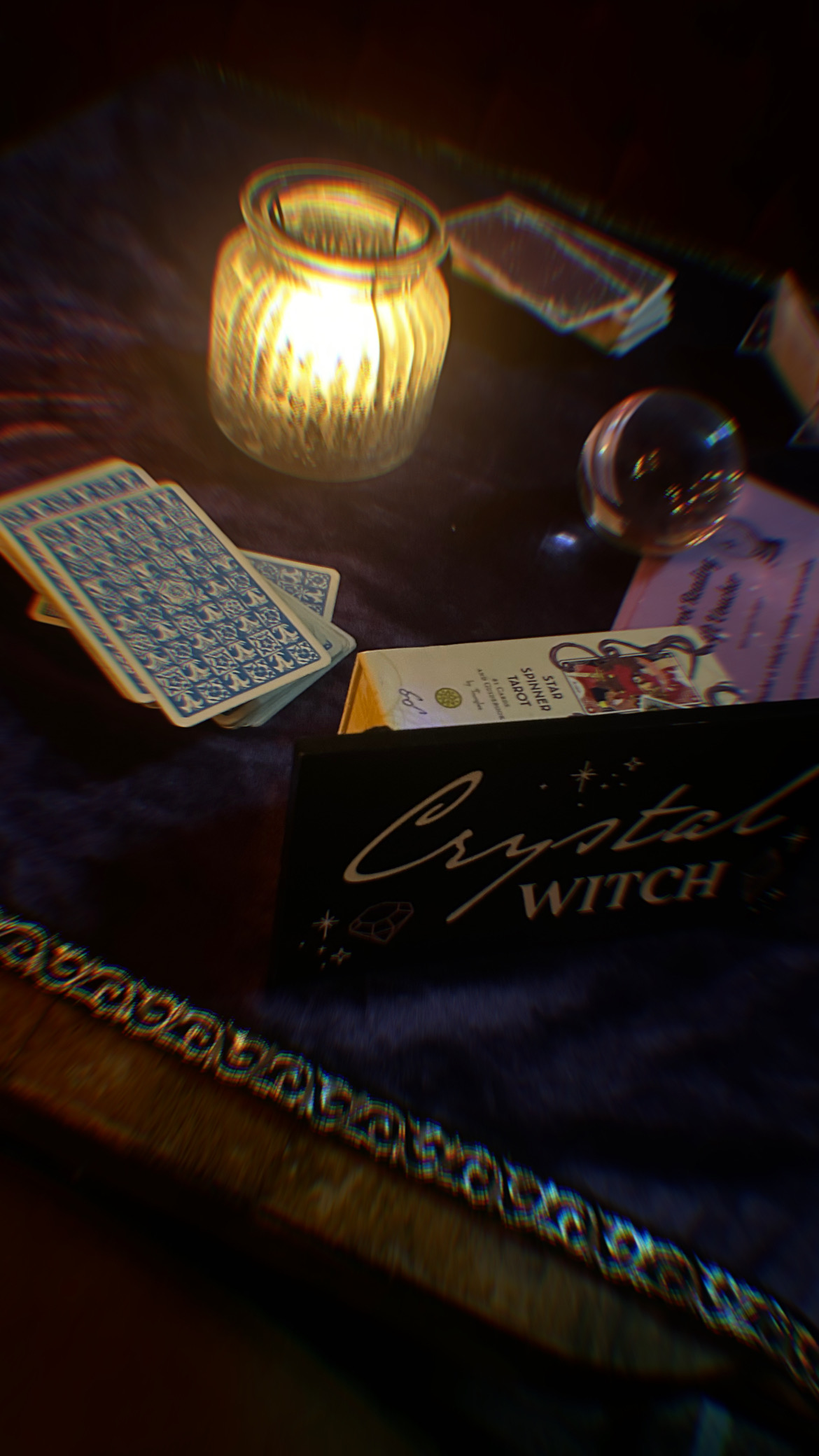Tarot cards, a crystal ball and a lit candle in a mystical setup